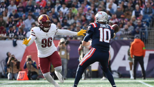 New England Patriots quarterback Mac Jones (10) throws the ball away while Washington Commanders defensive end James Smith-Williams (96) defends during the first half at Gillette Stadium.